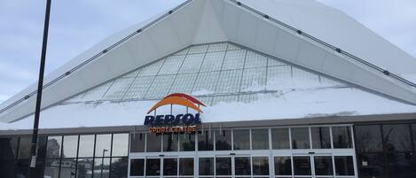 A building with a large glass facade and a triangular roof, labeled "REPSOL SPORT CENTRE".