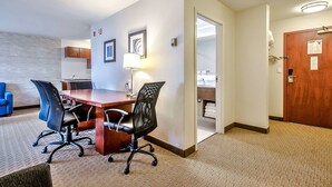 A conference room with a wooden table and four chairs, a desk with a computer, and a bathroom visible through an open door. - Comfort Inn And Suites South (Calgary)