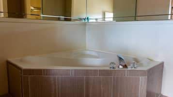Un baño moderno con una bañera independiente, una ducha con mampara de vidrio y un espejo grande sobre la bañera.