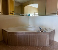 Un baño moderno con una bañera independiente, una ducha con mampara de vidrio y un espejo grande sobre la bañera.
