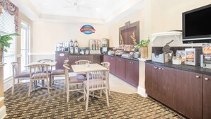 A breakfast area with a counter, seating, and a television. - Baymont by Wyndham Crestview (Crestview)