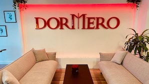 A living room with two sofas, a coffee table, and a wall-mounted sign reading "DORMERO". - DORMERO Hotel Bretten (Bretten)