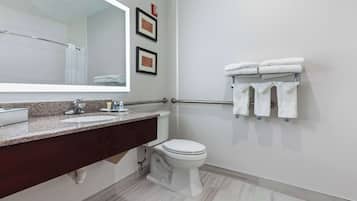 Un baño moderno con encimera de mármol, inodoro blanco y toallero con toallas dobladas.