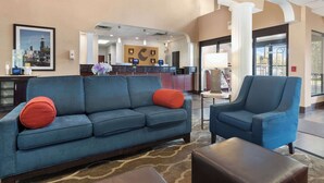 Un hall d’hôtel avec un canapé bleu, un fauteuil bleu et un comptoir d’accueil.