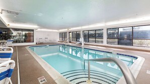 Une piscine intérieure à l'eau d'un bleu limpide, avec un bord carrelé et un escalier pour y accéder.