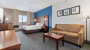 Une chambre d’hôtel avec un lit, un canapé, un bureau et une lampe.