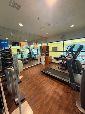 Un gimnasio con equipo de ejercicio, una cinta de correr y un espejo grande.
