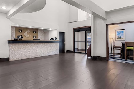 A hotel reception area with a reception desk, a large window, and a door leading to the lobby.