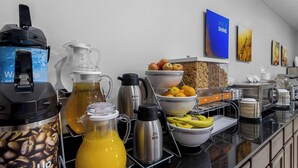 A breakfast buffet with coffee makers, a juice dispenser, and various fruits and cereals. - Comfort Inn & Suites near Tinley Park Amphitheater (Tinley Park)