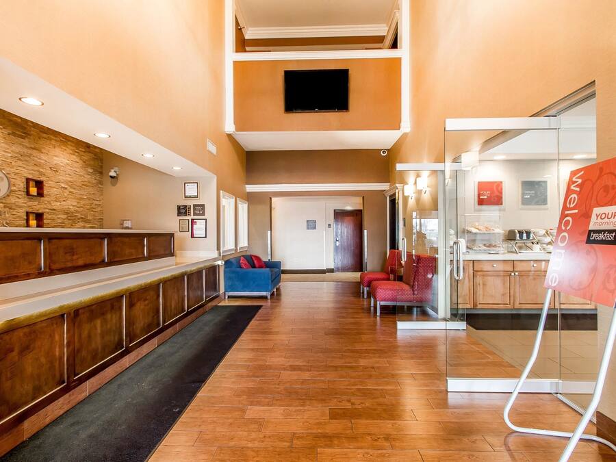 A hotel lobby with a reception desk, a blue sofa, a red chair, and a breakfast area.