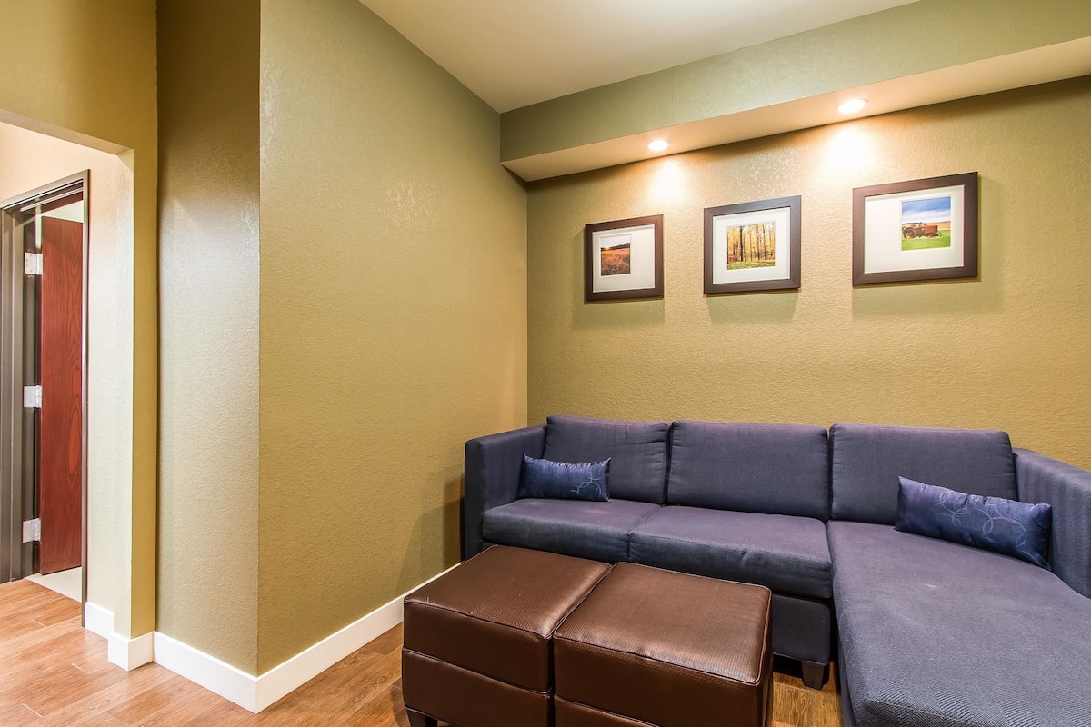 A living room with a sectional sofa, a brown ottoman, and three framed pictures on the wall.