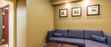 A living room with a sectional sofa, a brown ottoman, and three framed pictures on the wall.
