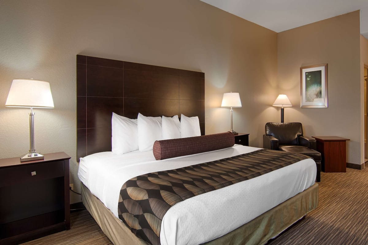 A hotel room with a large bed, two bedside lamps, a desk, and a chair.