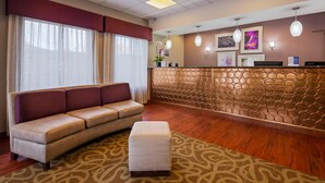 Un espace d’accueil comprenant un canapé, une petite table, un tapis à motifs, un mur décoratif et des luminaires suspendus.