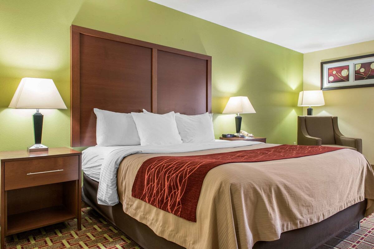 A hotel room with a large bed, two bedside tables, and a chair.