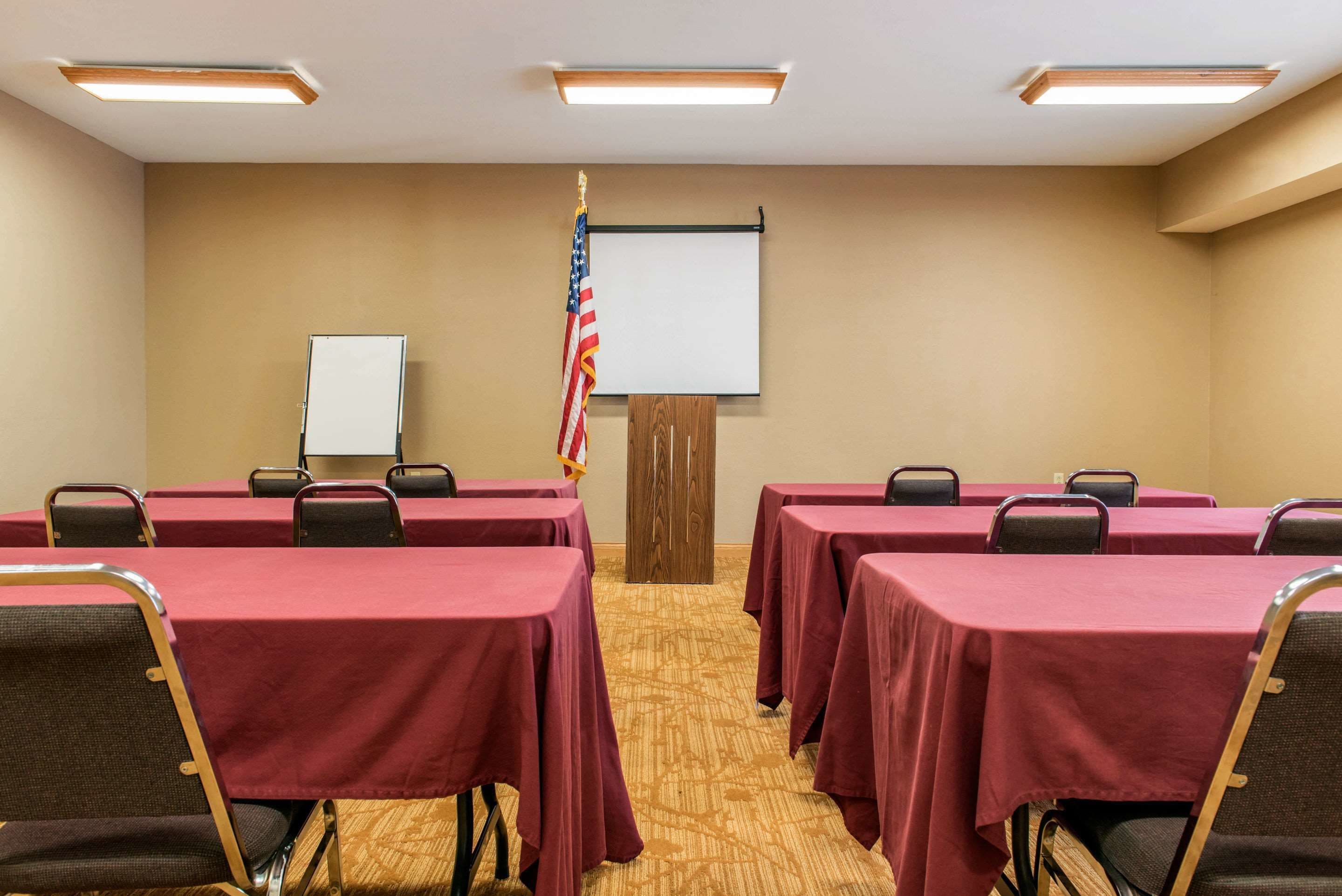 A conference room with tables, chairs, a whiteboard, and an American flag.