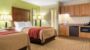A hotel room with two beds, a kitchenette, and a bathroom.