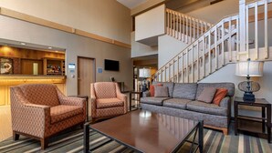 A spacious lobby with a staircase, a bar area, and seating arrangements including a sofa and armchairs. - Best Western Plus Chelsea Hotel (Monticello)