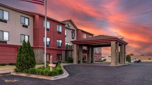 A hotel with a red and beige exterior, a covered entrance, and an American flag. - Best Western Plus Chelsea Hotel (Monticello)