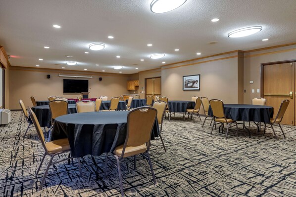 A conference room with multiple tables and chairs, carpeted floor, and recessed ceiling lights.