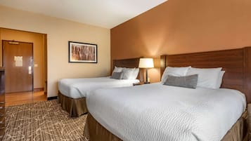 A hotel room with two beds, a wooden headboard, a framed picture on the wall, and a carpeted floor.