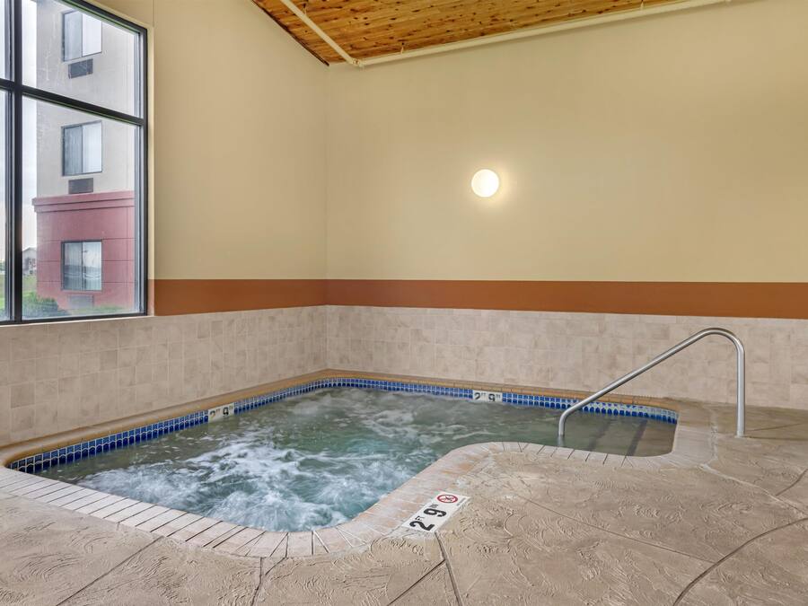 A hot tub with a tiled edge, a metal handrail, and a sign indicating the depth.