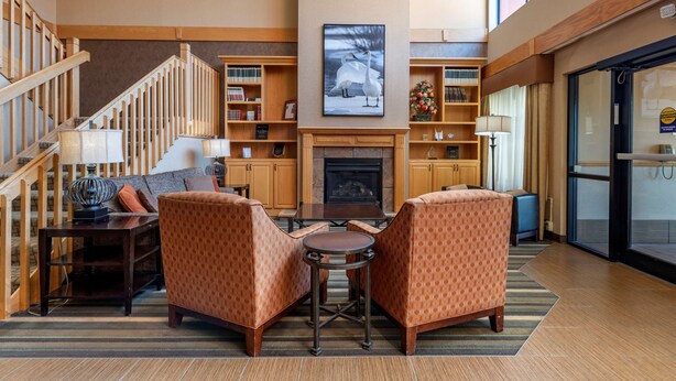 A spacious living area with a fireplace, a staircase, and a view of the outdoors. - Best Western Plus Chelsea Hotel (Monticello)