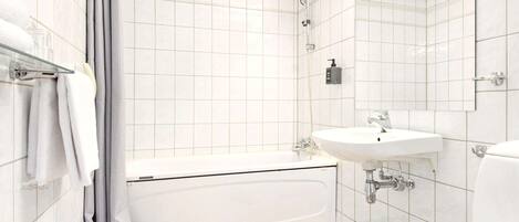 Een moderne badkamer met witte tegels, een badkuip, een wastafel en een toilet.