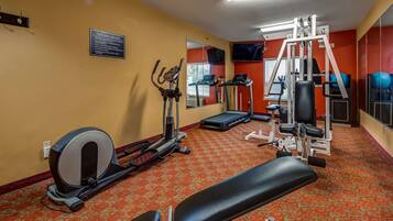 A fitness center with cardio machines, a weight bench, and a mirror.