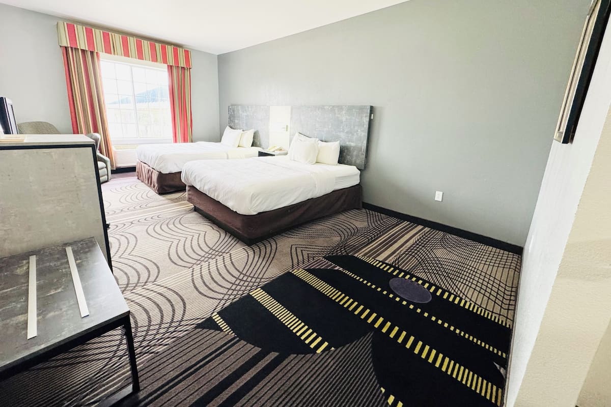 Quarto de hotel com duas camas, uma escrivaninha e vista para a cidade.