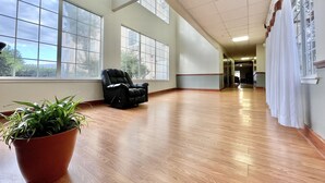Un hall d’entrée spacieux, doté de grandes fenêtres, d’un fauteuil en cuir noir et d’une plante en pot.