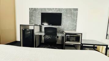 Une chambre d’hôtel équipée d’un lit, d’un bureau, d’une chaise, d’une télévision et d’un four à micro-ondes.