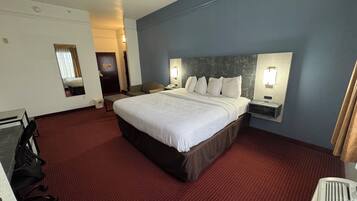 Habitación de hotel con una cama grande, dos mesitas de noche con lámparas, un escritorio con silla y un espejo en la pared.