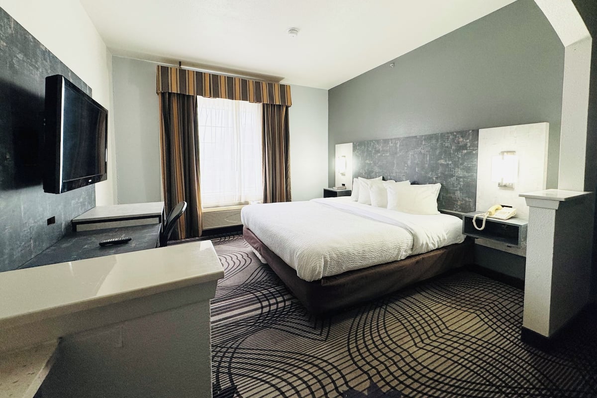 Quarto de hotel com uma cama, televisão, escrivaninha e telefone.