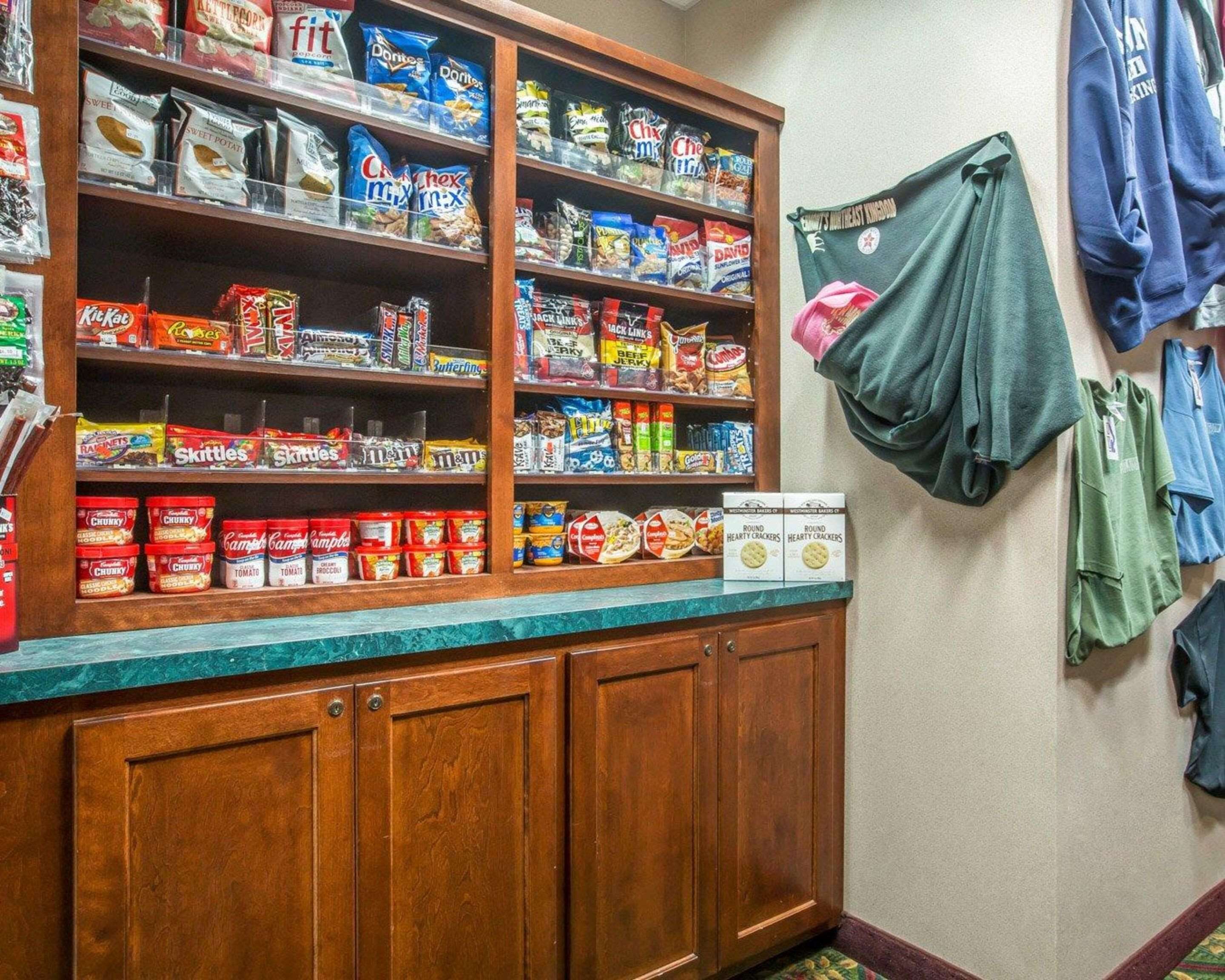 Un garde-manger bien garni de diverses collations et céréales, des armoires en bois et un mur où sont suspendus des vêtements.