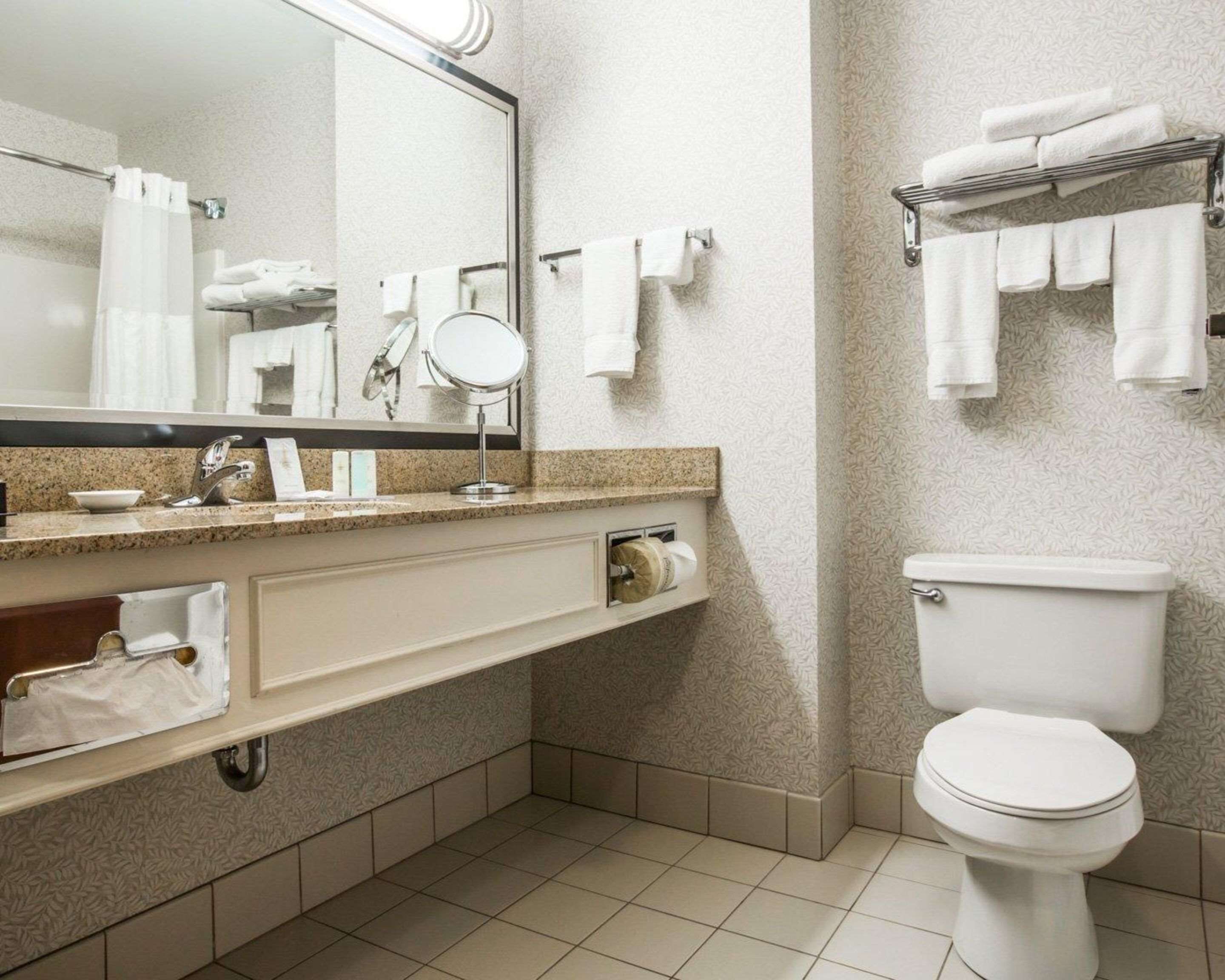 A modern bathroom with a sink, mirror, towel rack, toilet, and patterned walls.