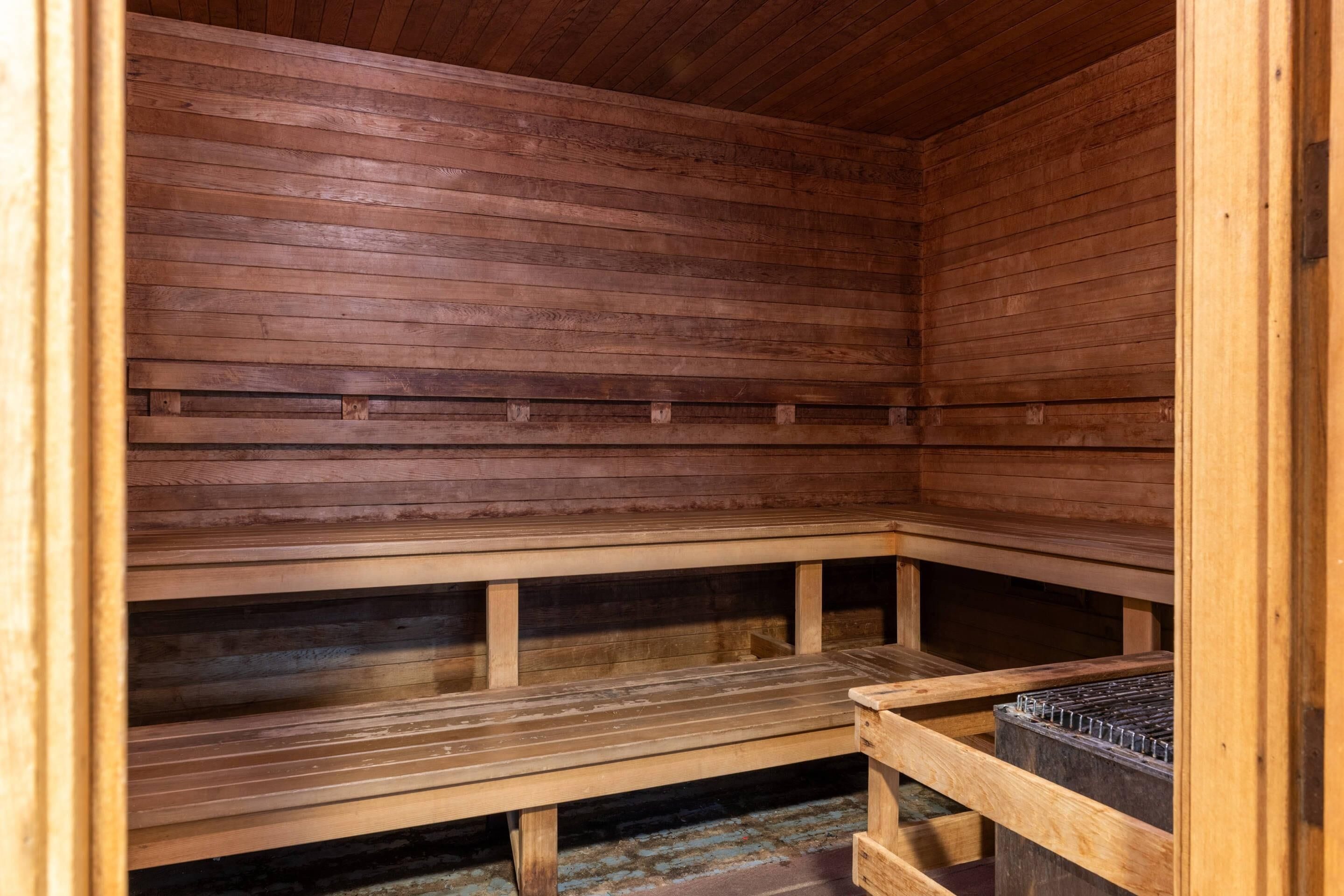 A wooden sauna with benches and a metal heater.