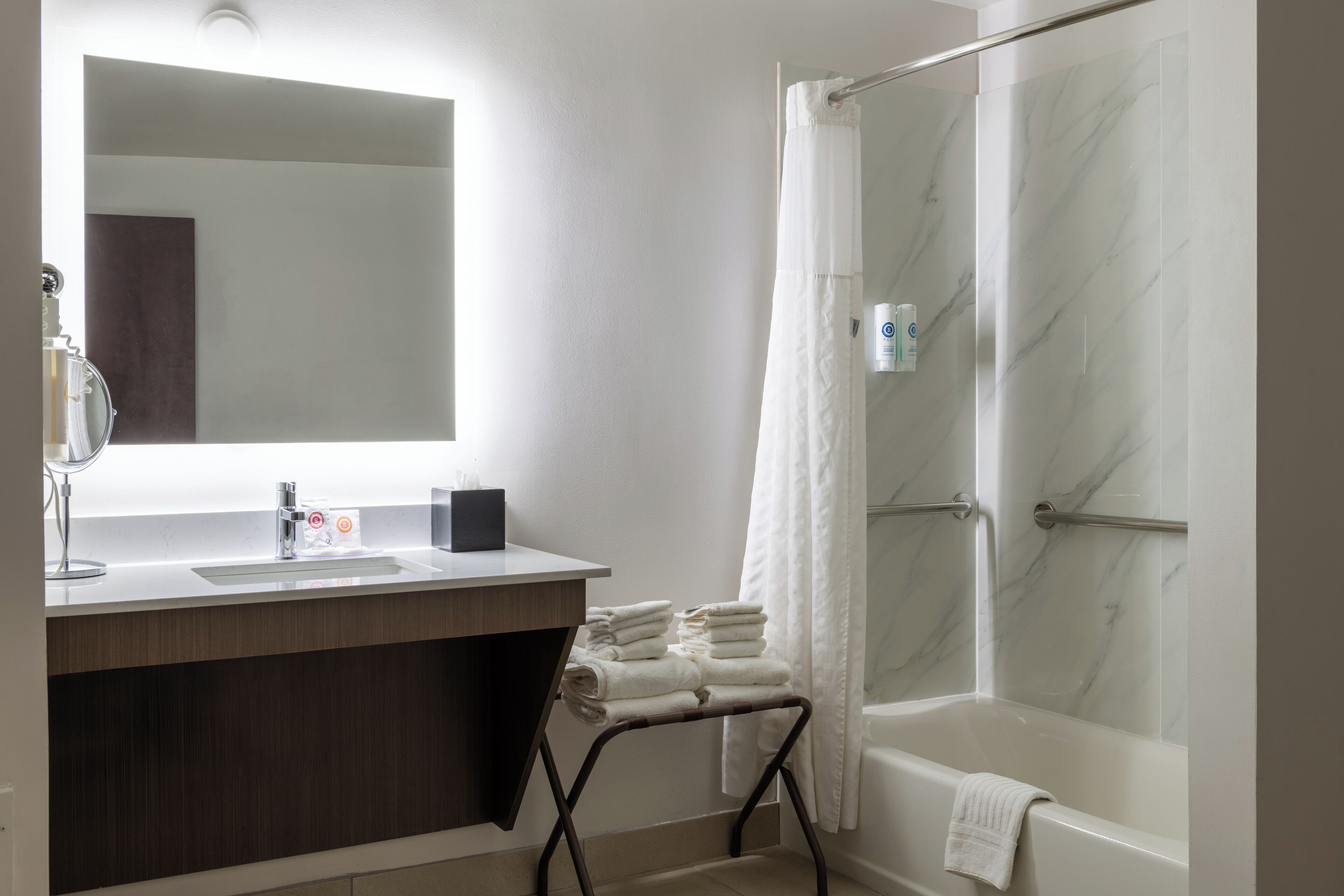 A modern bathroom with a marble shower, a sink with a mirror, and a towel rack.