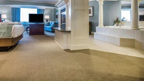 A hotel room with a large bed, a TV, a sofa, and a bathroom with a sink and mirror. - Comfort Inn & Suites Near Burke Mountain (St. Johnsbury)