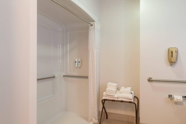 A bathroom with a shower, a towel rack, and a hand sanitizer dispenser.