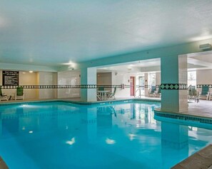 Une piscine intérieure à l’eau claire, entourée de chaises longues et agrémentée d’un panneau indiquant les règles d’utilisation de l’espace piscine.