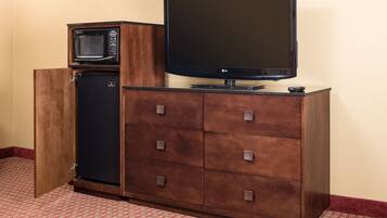 Een kleine kitchenette met een magnetron, koelkast en een flatscreen televisie op een houten kast.