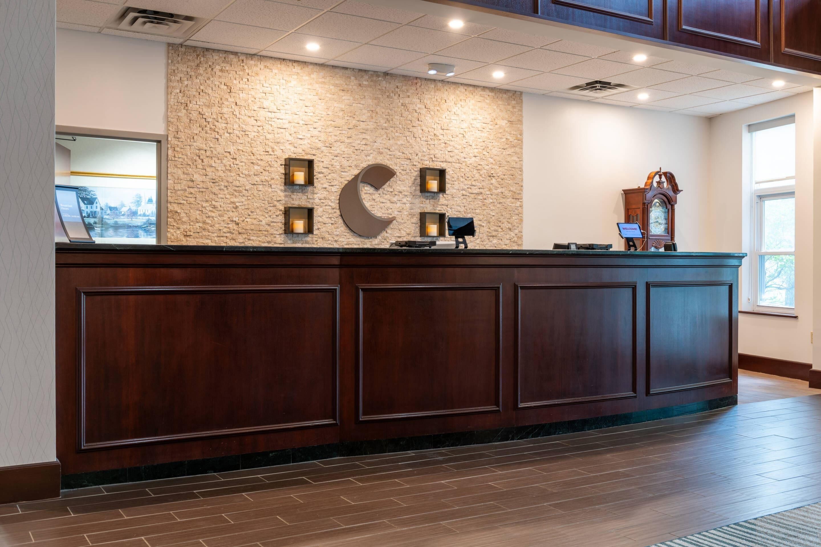 A reception desk with a stone wall backdrop, a clock, and a view of the outside.