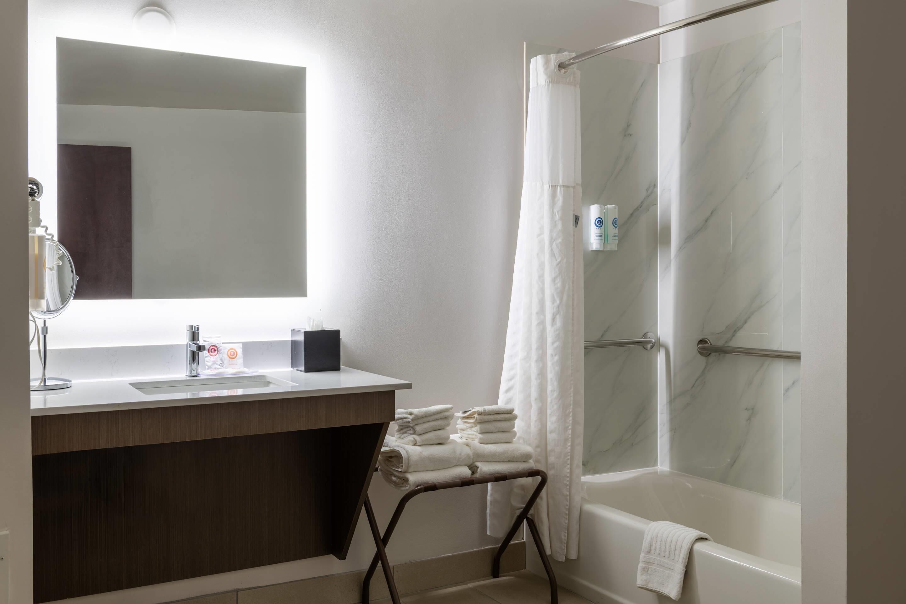 A modern bathroom with a marble shower, a sink with a mirror, and a towel rack.