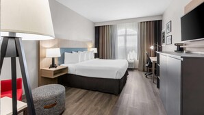 A hotel room with a bed, bedside tables, a desk, a chair, a lamp, a TV, and a window with curtains. - Country Inn & Suites by Radisson, Tucson Airport, AZ (Tucson)