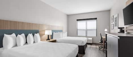 A hotel room with two beds, a desk, a TV, and a large window.