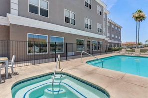 A swimming pool area with a pool, a fence, and a building with windows.