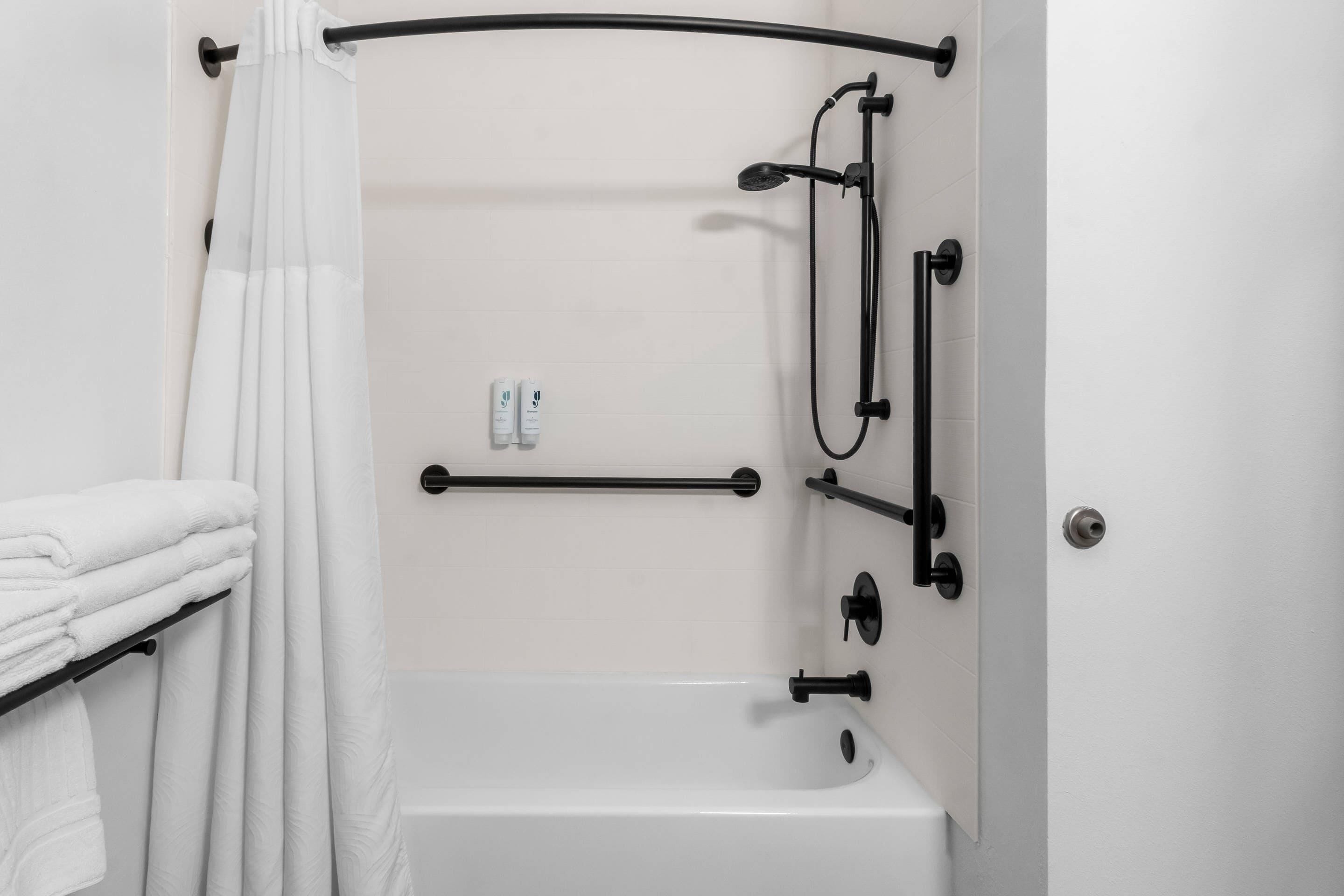 Un baño con bañera, toallero, barra de cortina de ducha y baranda.