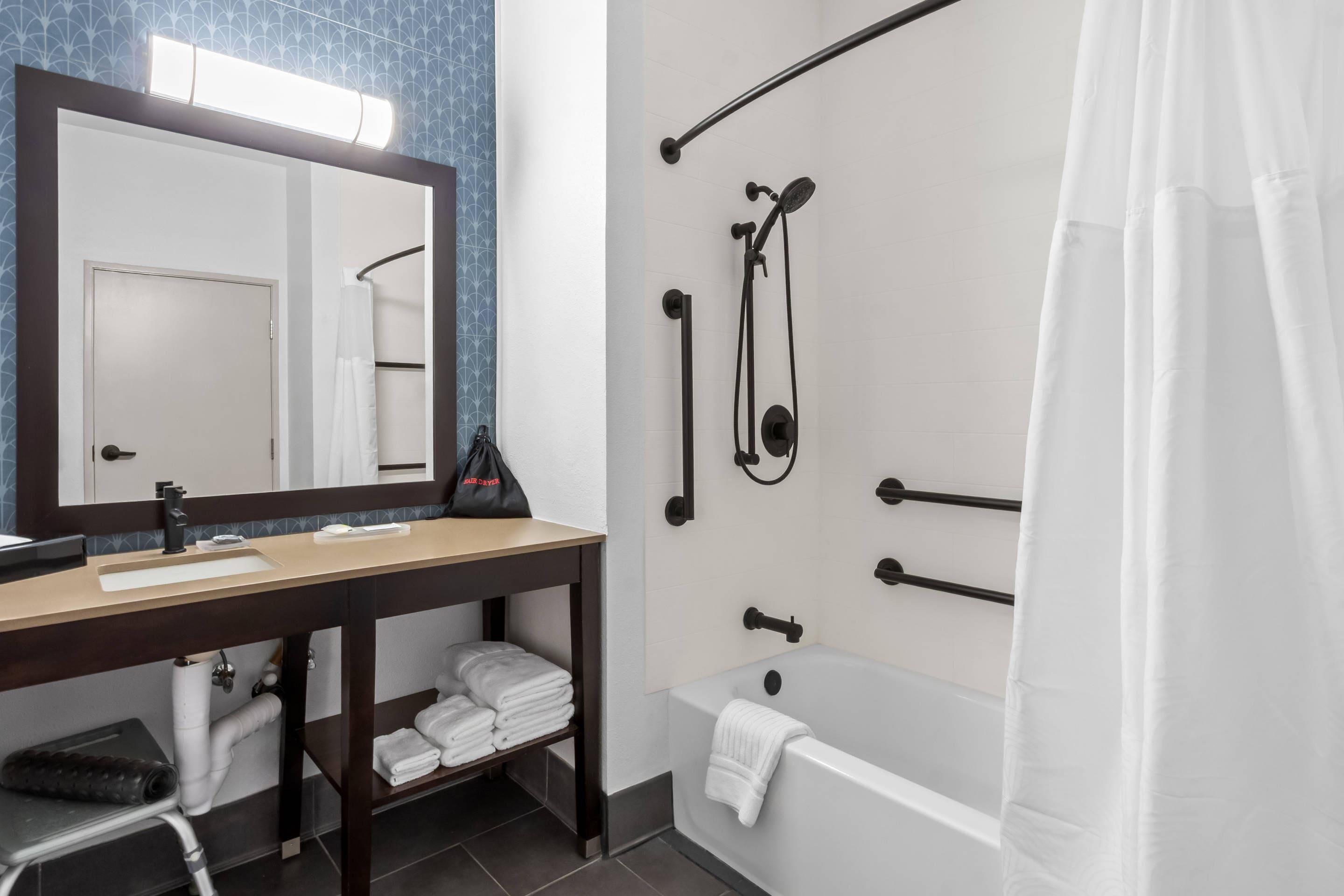 A modern bathroom with a sink, mirror, towel rack, shower, and bathtub.