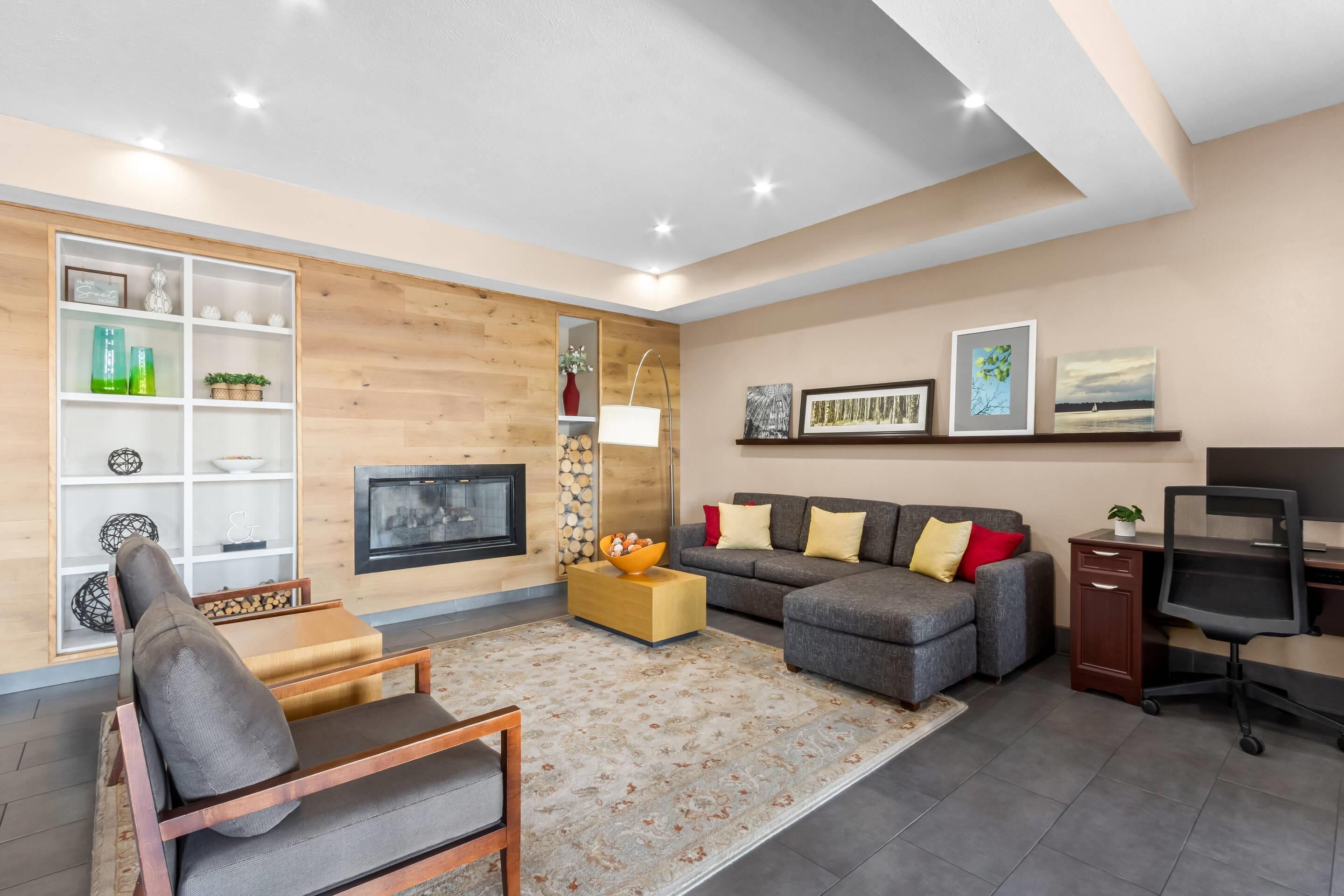 Uma sala de estar moderna com sofá, poltrona, televisão, lareira e objetos decorativos.